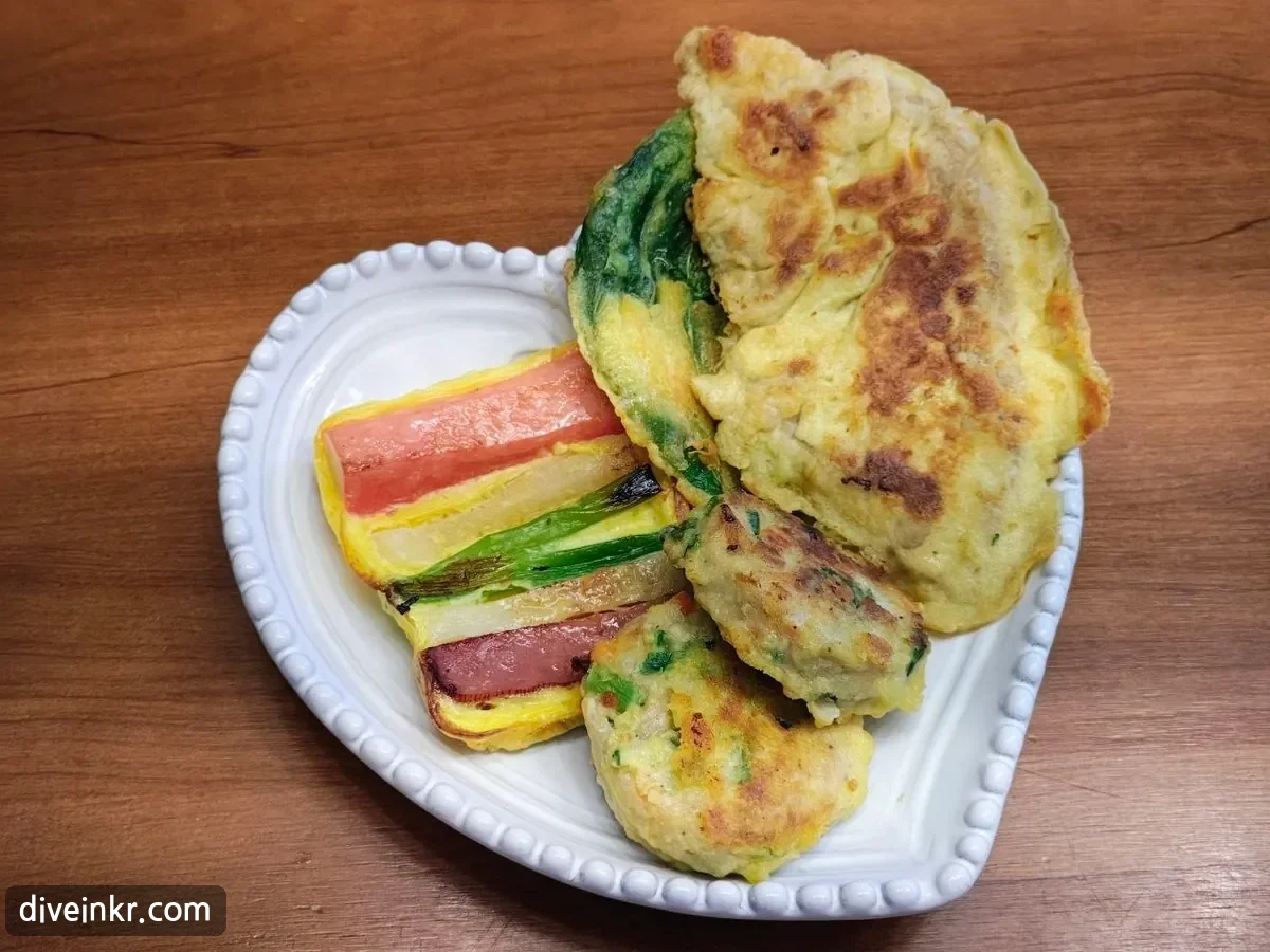 A heart-shaped white plate with four kinds of Korean jeon: striped skewer slices of crab stick, pickled radish, scallion and ham, a large piece of beef jeon, a green perilla-leaf jeon, and two round meat patties